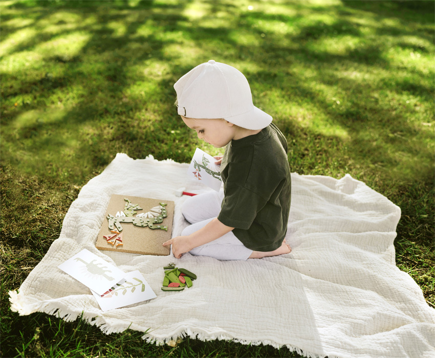 Child hammering wooden shapes onto cork board
