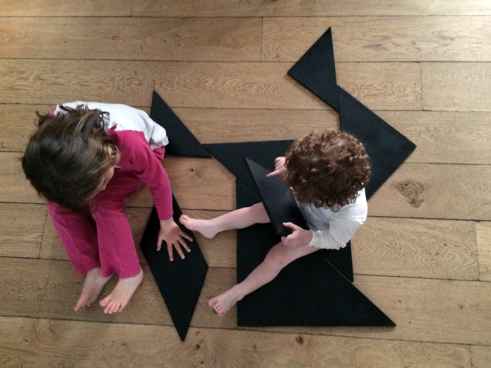 Children collaborating with wooden tangram puzzle